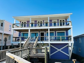A multi-story beachfront building with a wooden deck and stairs leading to the upper levels. - Nothin But Nett 5 Bedroom Home by RedAwning (Supply)