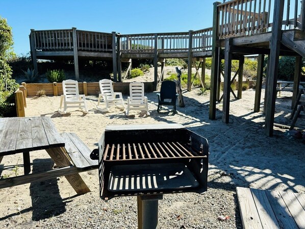 Eine Holzterrasse mit Grill, Liegestühlen und einem Holztisch.