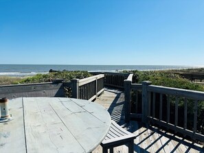 A wooden deck with a table and benches overlooking the ocean.