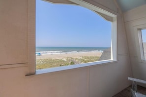 A room with a large window overlooking a beach.