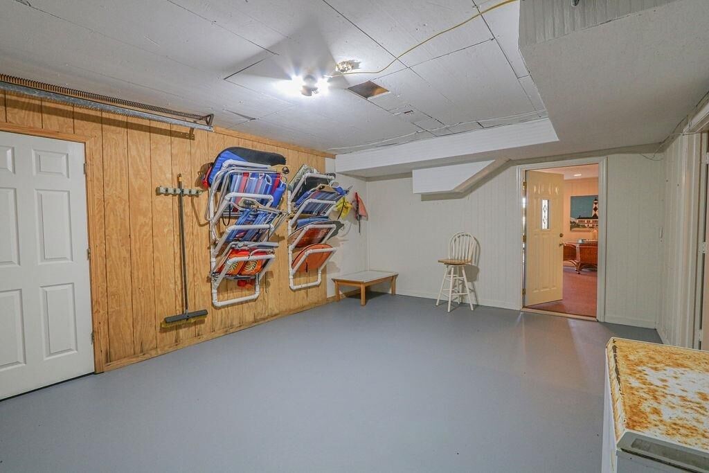 Une pièce dotée d’une porte en bois, d’un porte-chaises fixé au mur, d’une petite table en bois et d’un passage menant à une autre pièce.