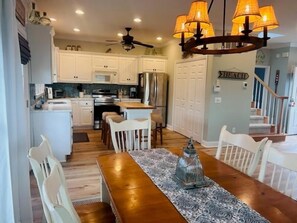 Una cocina amplia con armarios blancos, una mesa de comedor de madera y una araña.
