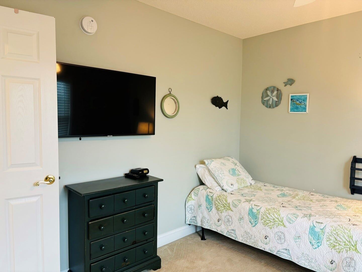 A bedroom with a bed, dresser, television, and wall decorations.