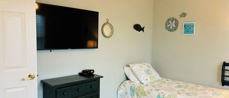A bedroom with a bed, dresser, television, and wall decorations.