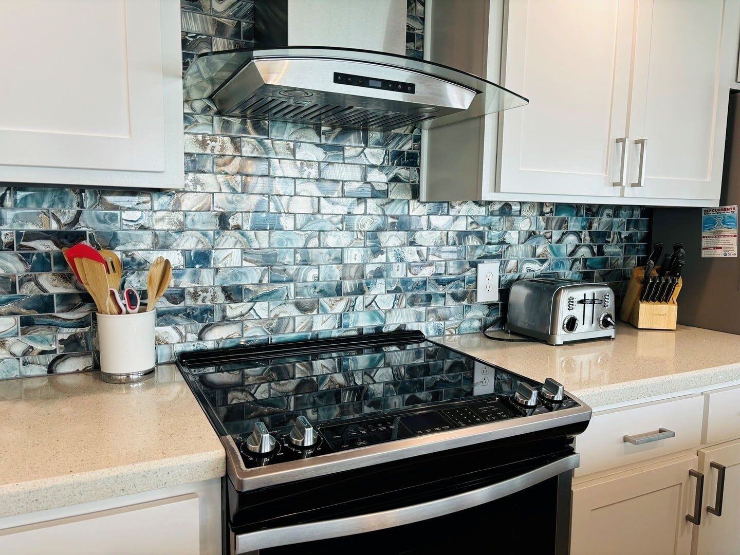 Cozinha com fogão a gás, torradeira e painel de backsplash com padrão azul e branco.