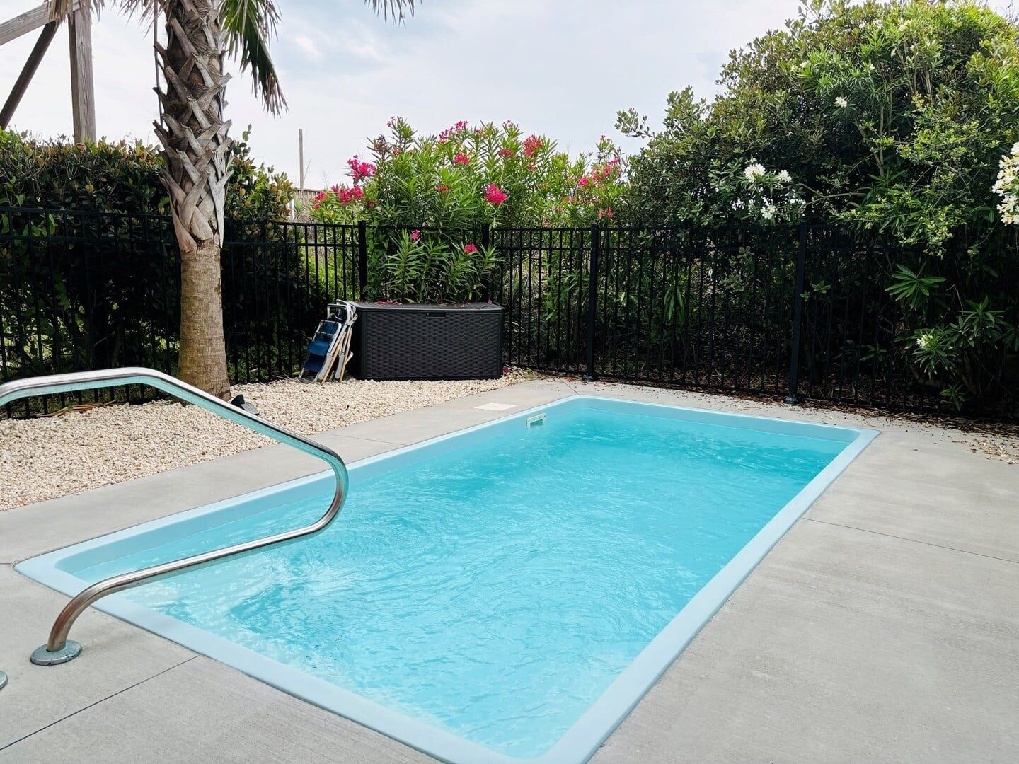 Una piscina rettangolare con una scala metallica su un lato, circondata da un solarium in cemento.