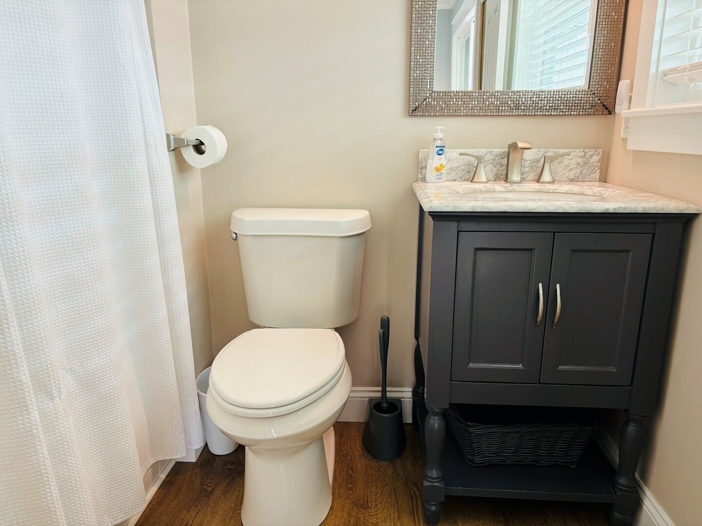 A bathroom with a toilet, a sink, a mirror, and a shower curtain.