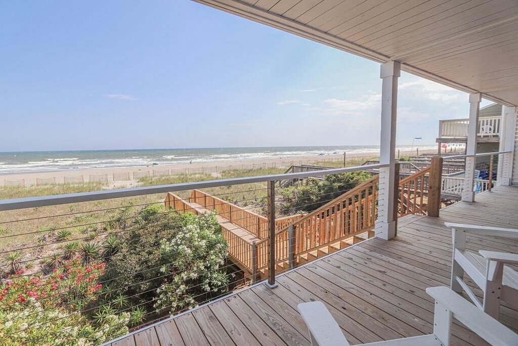 A wooden deck with a view of the beach and ocean.