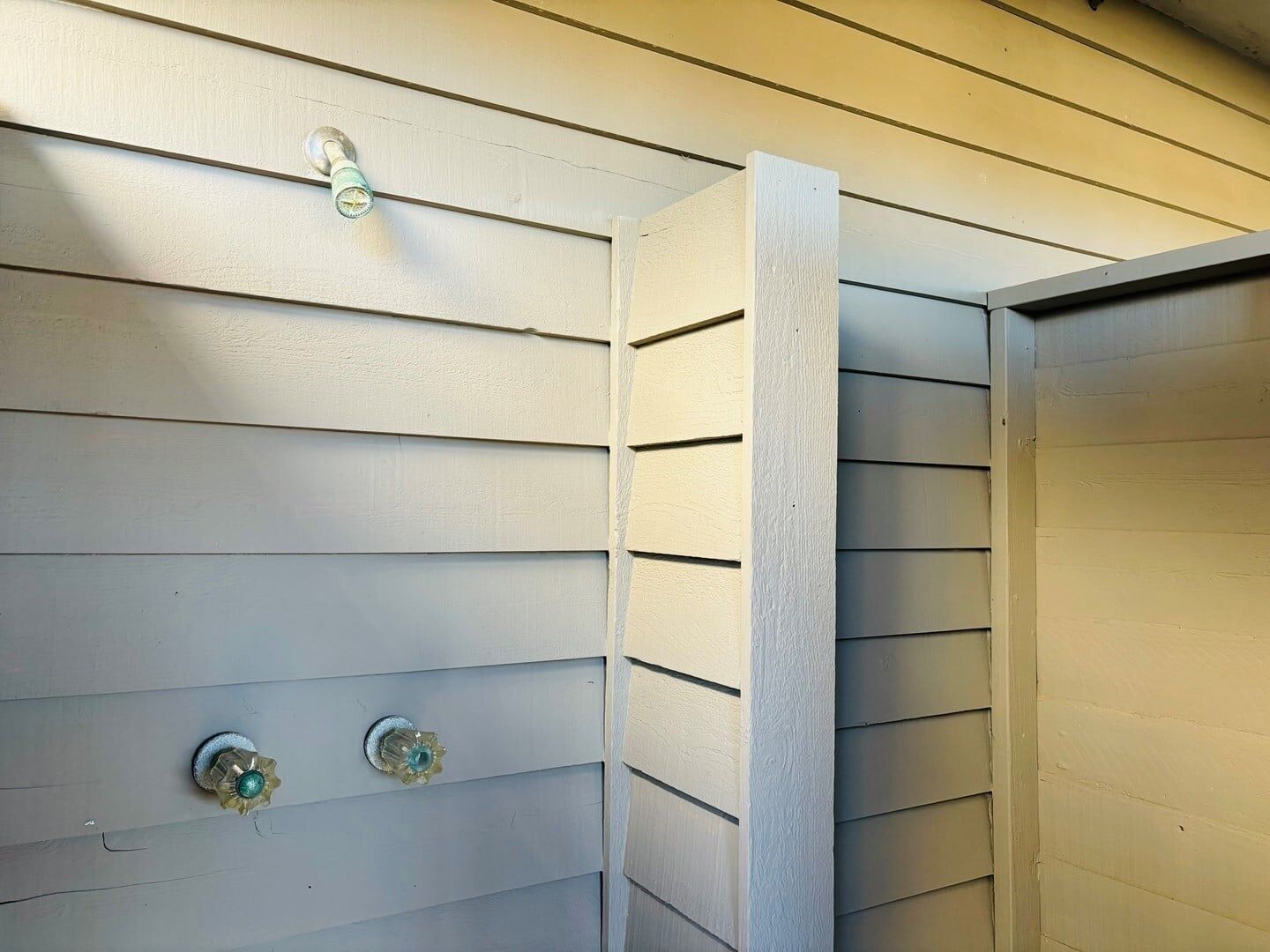 A corner of a room with white siding and a vertical wooden beam.