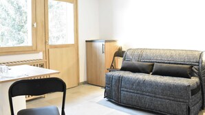 A compact living space with a kitchenette, a dining table, and a sofa.