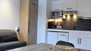 A modern kitchen with a microwave, coffee maker, and dishwasher. There is a dining table with plates and cutlery.