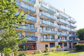 A multi-story residential building with balconies, a garden area, and a clear sky. - Spacious, modern apartment for up to 4 people (Ostfildern)