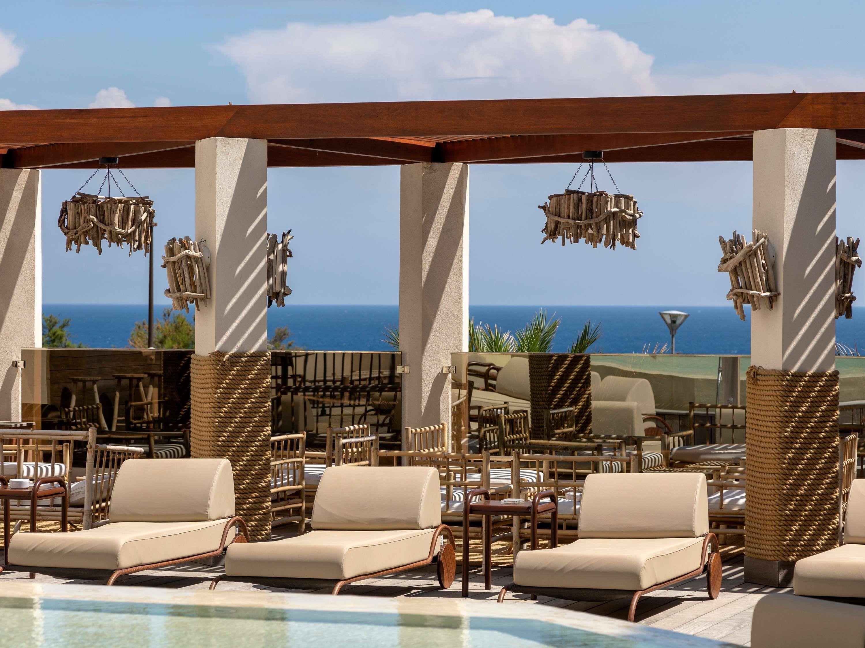 Un espace aménagé au bord de la piscine, avec des chaises longues et une vue sur l’océan.
