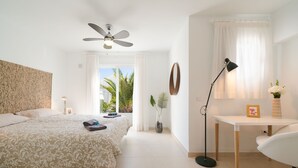 A bedroom with a bed, a desk, a chair, a ceiling fan, and a window with curtains. - Luxurious A2 in a small complex with communal pool 100m from the sea (Charco del Palo)