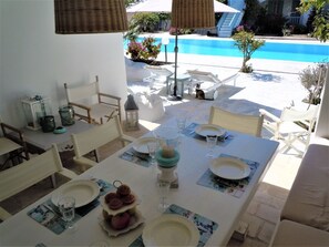 Ein Essbereich Blick auf den Pool, mit Tisch, Geschirr, Gläsern und einem Etagenkuchenständer.