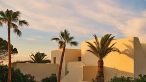 A modern building with palm trees and a paved pathway. - NOŪS Santorini (Santorini)