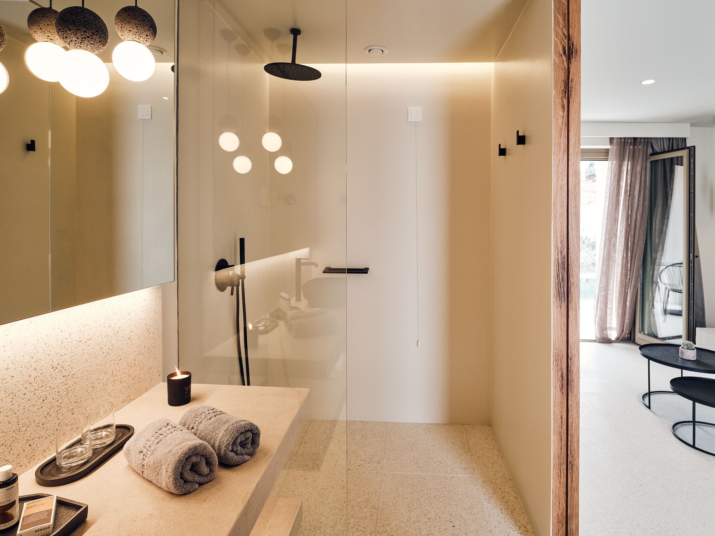 Un baño moderno con cabina de ducha de vidrio, tocador con espejo y bandeja con toallas y artículos de aseo.