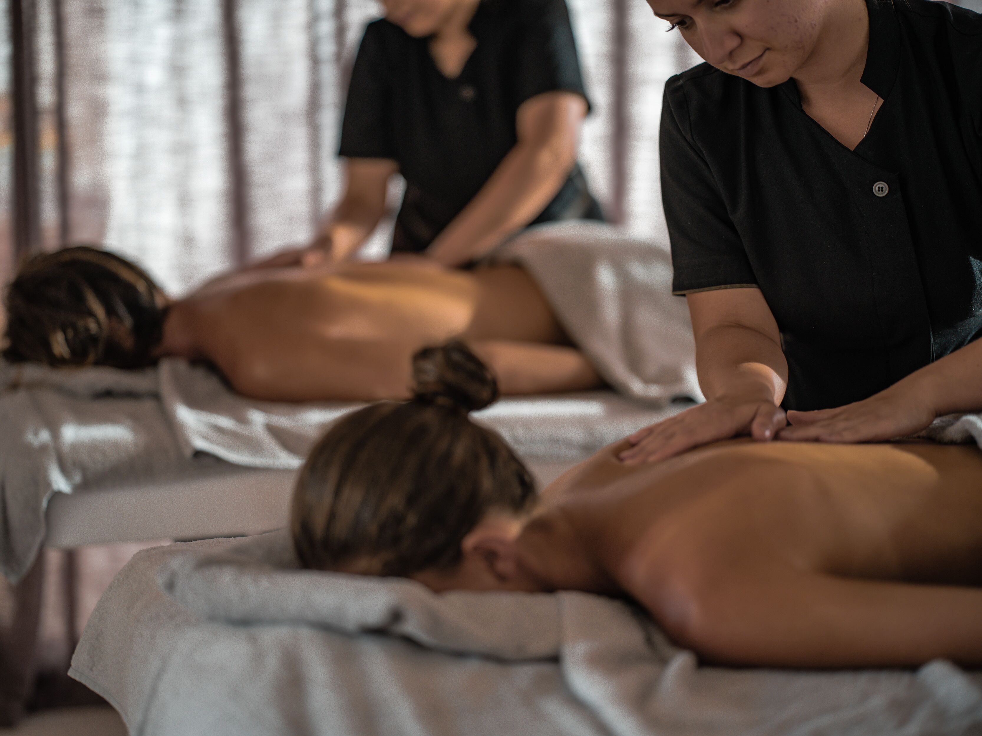 A massage therapy session in a room with a bed and a massage table.