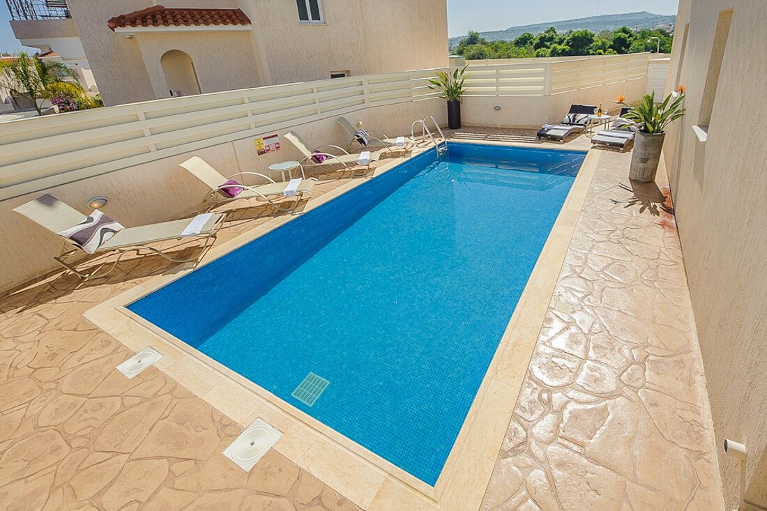 Una piscina rectangular amb un videt de rajoles, envoltada de gandules i un solàrium de pedra.