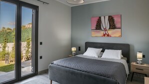 A bedroom with a large bed, two bedside tables with lamps, a painting on the wall, and a sliding glass door leading to a balcony. - Villa Mariliza, ιδανική επιλογή για να αποδρά... (Argostoli)