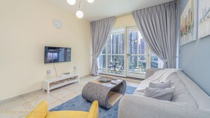A modern living room with a grey sofa, a yellow armchair, a flat-screen TV, and a large window with curtains. - Marco Polo - Striking Lake Views at JLT | 1 BR | 2 Balconies (Dubai)