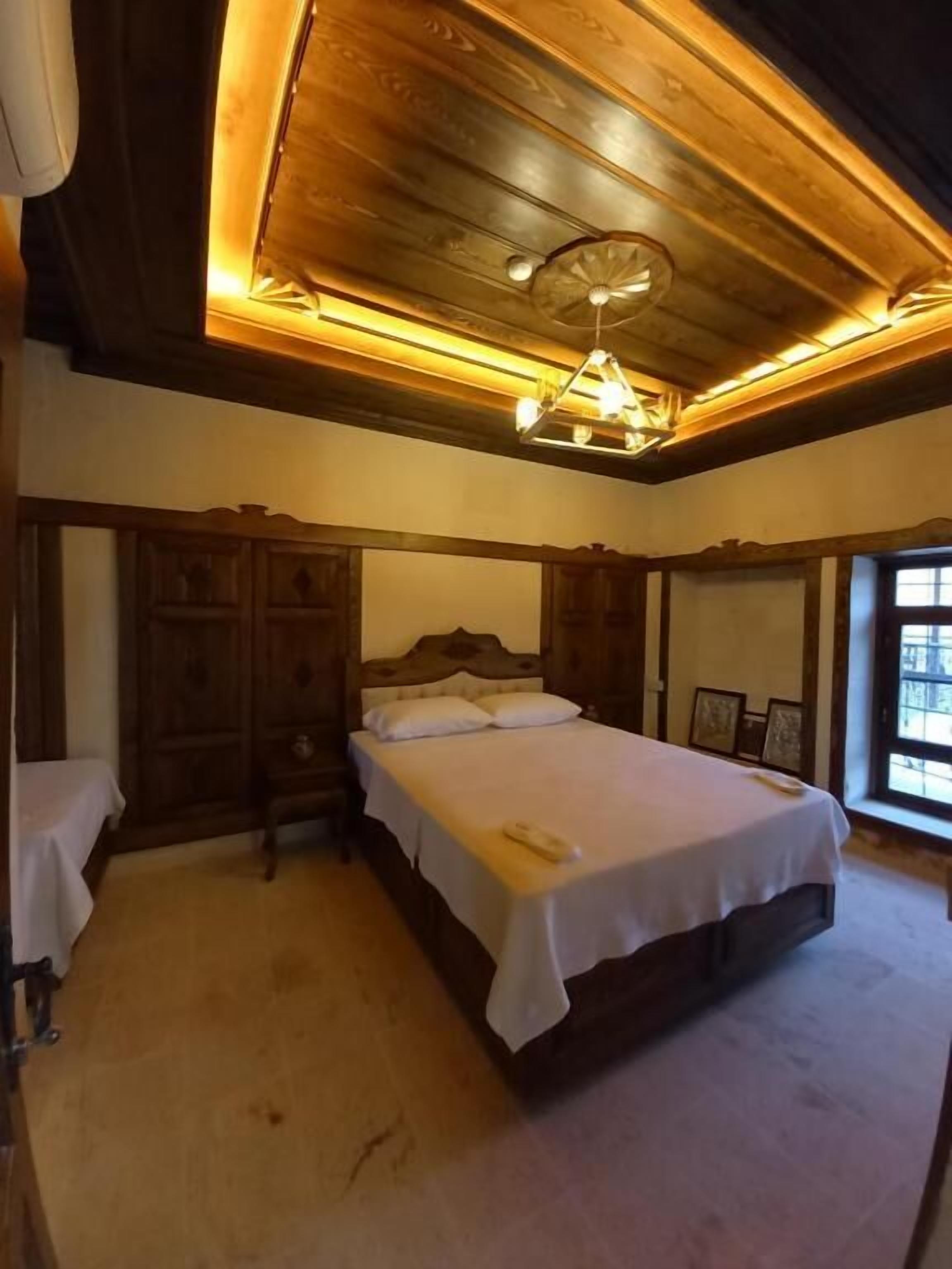 A bedroom with a large bed, wooden headboard, and a ceiling light fixture.