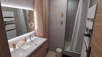 Ein modernes Badezimmer mit Waschtisch, Spiegel und Dusche.