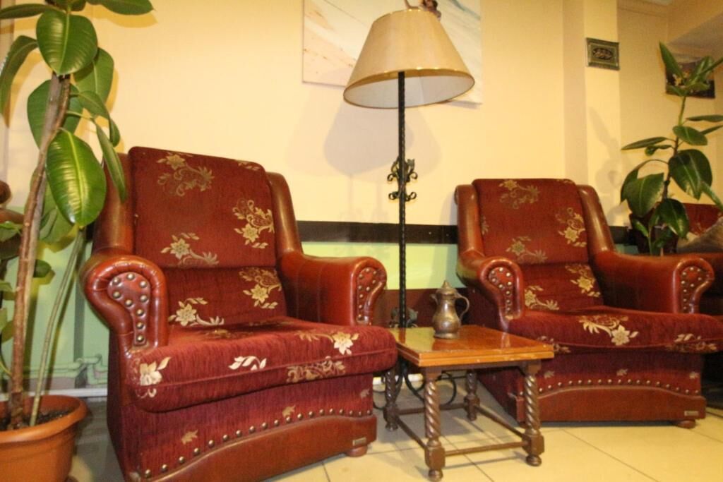 Two ornate armchairs with floral upholstery, a floor lamp, and a small table.