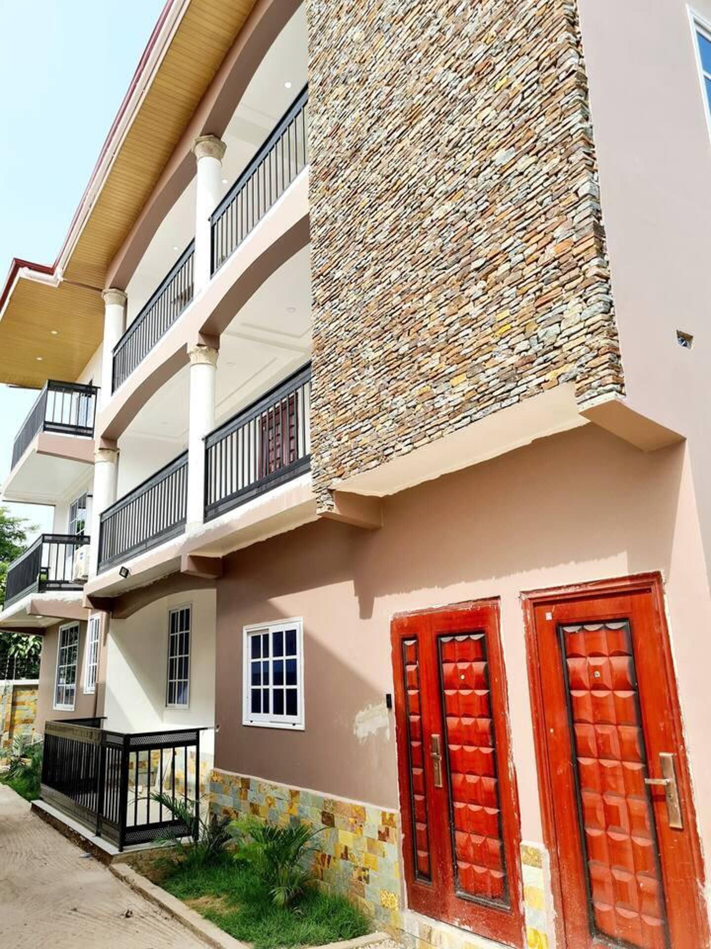 Un edificio a più piani con balconi, facciata in pietra e porte rosse.