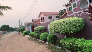 Une rue résidentielle bordée de maisons, avec un chemin de terre et de la verdure.