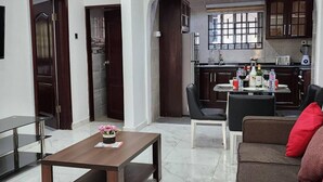 A modern living room with a dining area, a kitchen in the background, and a large window. - Cozy,quiet & Fantastic- Close to Highway - Parking (Adenta)