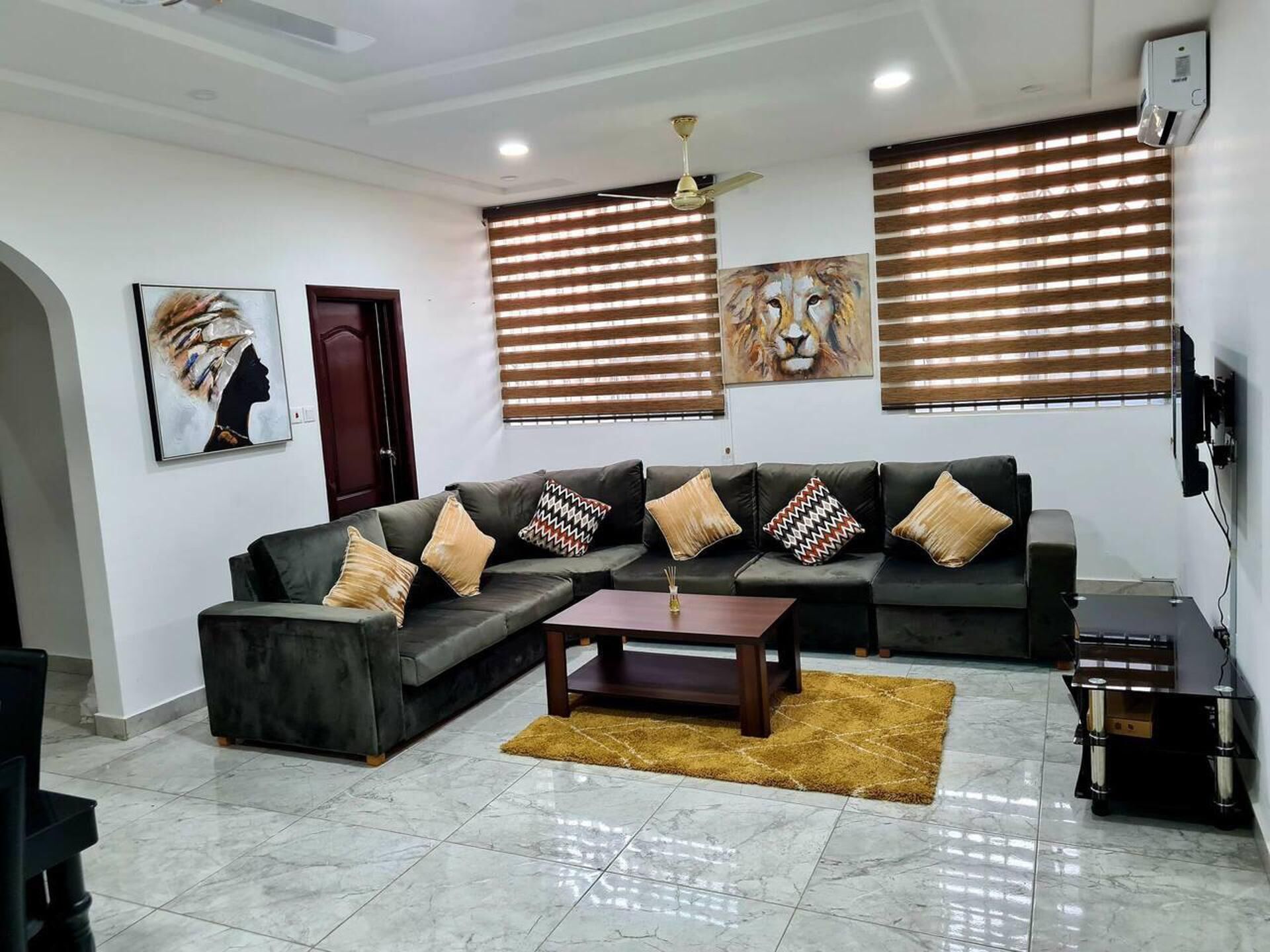 A modern living room with a sectional sofa, a coffee table, and a TV mounted on the wall.