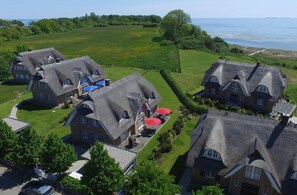 A large estate with multiple houses, a well-maintained lawn, and a view of the sea.