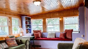 Un salon chaleureux avec un plafond en bois, un banc intégré agrémenté de coussins et un tapis coloré tissé.