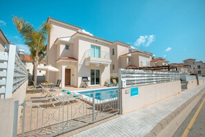 A two-story building with a swimming pool, outdoor seating, and a gated entrance.
