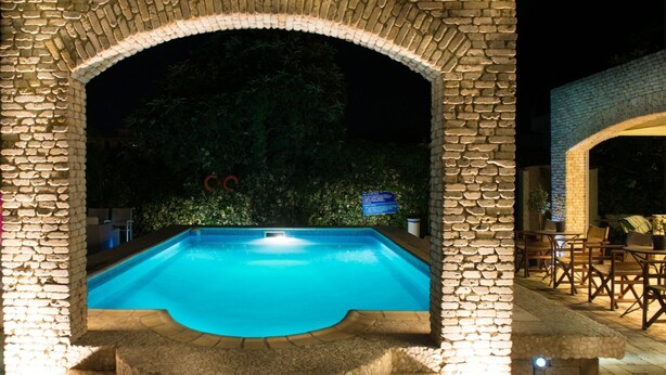 Una piscina exterior amb un arc de pedra, envoltada d'escales de pedra i zones d'estar a l'aire lliure.