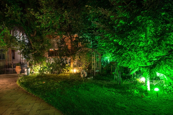 A garden pathway with a gazebo, surrounded by lush greenery and illuminated by green lights. - Villa Edem (Thasos)