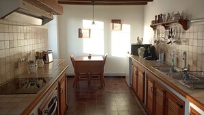 A kitchen with wooden cabinets, a tiled backsplash, a wooden dining table, and a window providing natural light.