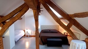 A bedroom with a sloped ceiling, a bed, a nightstand, a small table, and a chair.