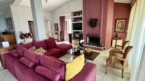 Een woonkamer met een grote hoekbank, een open haard en een decoratieve fauteuil.