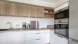 Een moderne keuken met houten kastjes, roestvrijstalen apparatuur en een inbouwoven.