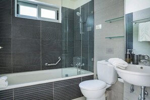 Enjoy a contemporary bathroom experience with a sleek shower area, glass-enclosed tub, and modern fixtures.