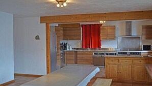 Une cuisine moderne avec des meubles en bois, un rideau rouge et un four à micro-ondes encastré.