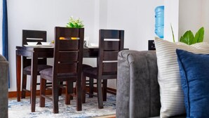 Een eetgedeelte met een tafel, stoelen, een waterdispenser en een plant.