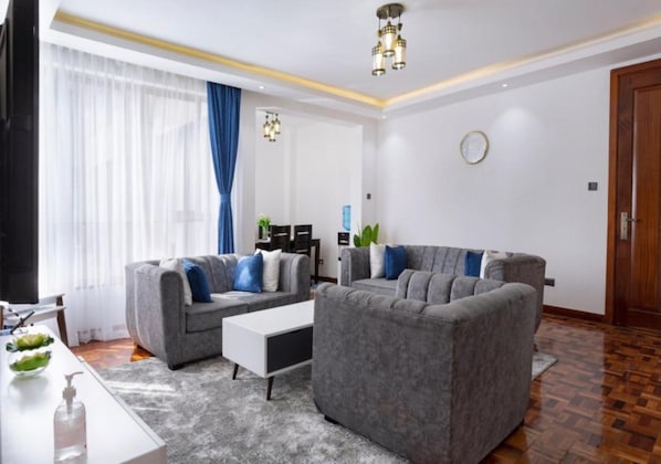 A modern living room with two grey sofas, a white coffee table, and a wooden floor. - Serene Heights Kileleshwa by Edmor (Nairobi)