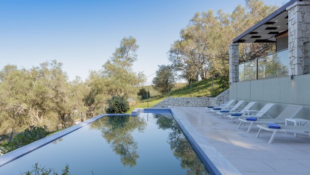 A swimming pool with lounge chairs and a stone wall. -  Villa Breeze & Villa Coco by Konnect Avlaki Beach (Corfu)