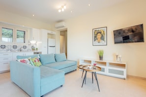 A modern living room with a light blue sofa, a round coffee table, and a white entertainment unit.
