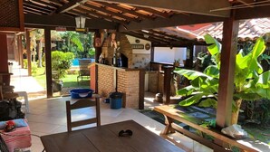 An outdoor patio area with a wooden table, a bench, and a brick counter. - Pousada Casa da Aroeira (Búzios)