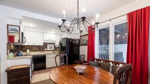 Une cuisine moderne avec des meubles blancs, un réfrigérateur noir et une table à manger en bois, accompagnée de chaises.