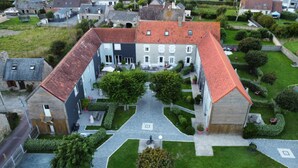 Vue aérienne d’une cour intérieure avec un chemin central, entourée de bâtiments aux toits recouverts de tuiles rouges et aux murs blancs.